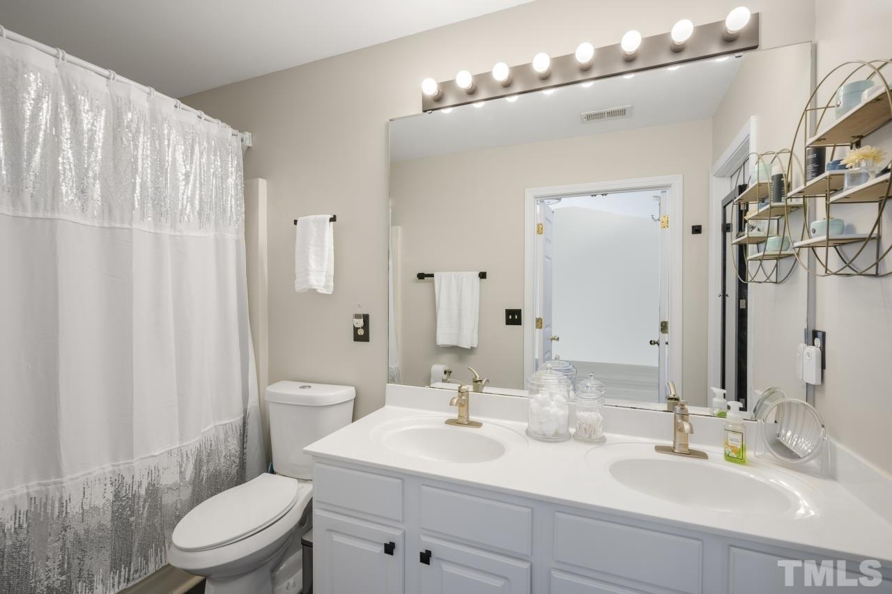 7106 Proctor Hill Drive Raleigh, NC 27613 - Photo 22 of 29 a bathroom with a double vanity sink toilet and a mirror