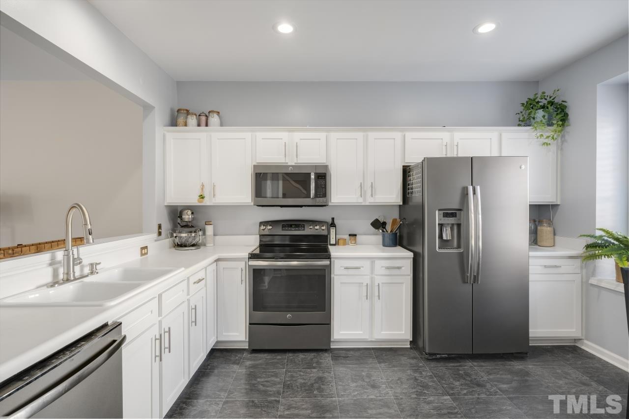 7106 Proctor Hill Drive Raleigh, NC 27613 - Photo 6 of 29 a kitchen with a refrigerator sink and white cabinets