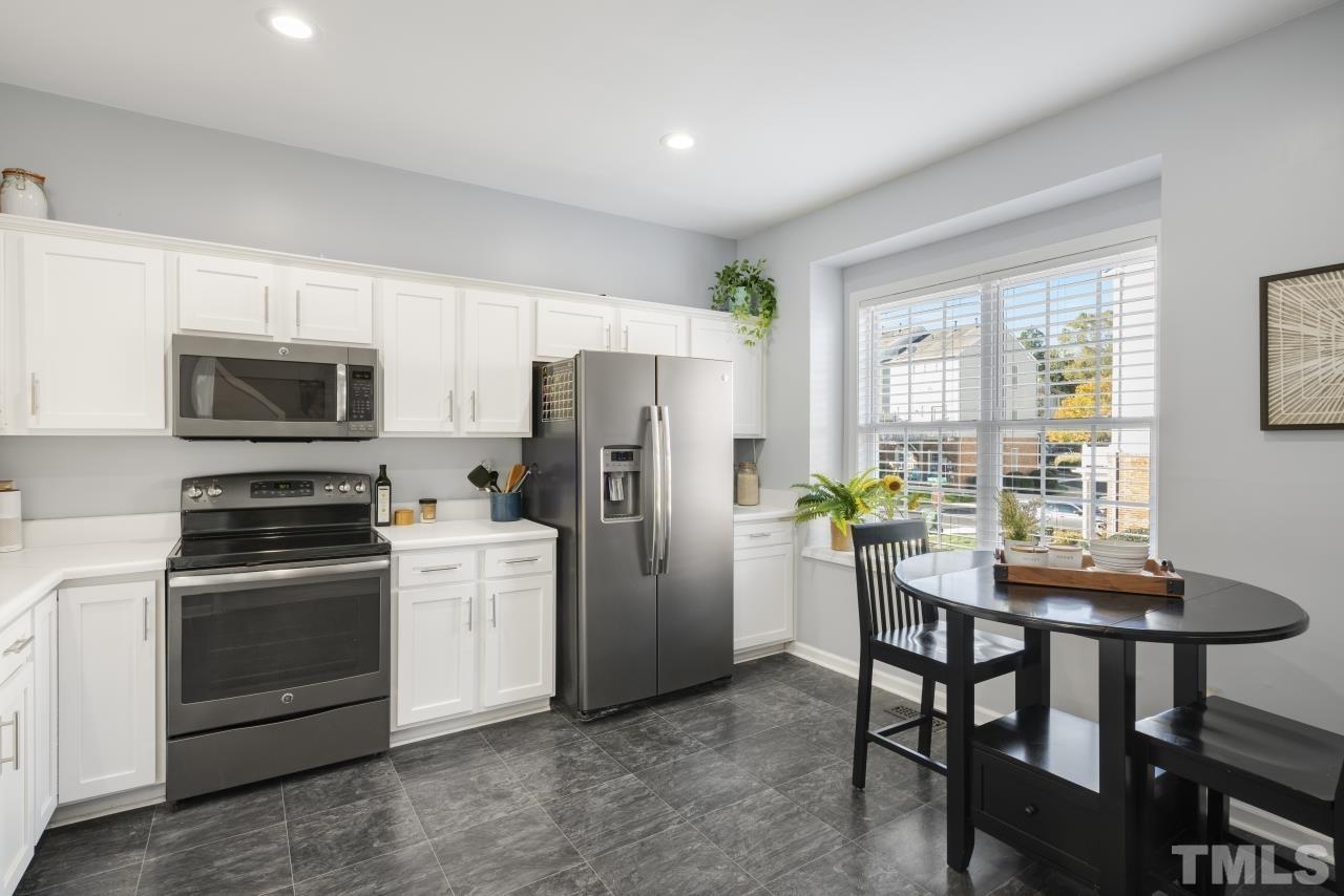 7106 Proctor Hill Drive Raleigh, NC 27613 - Photo 7 of 29 a kitchen with stainless steel appliances a dining table chairs stove refrigerator and microwave