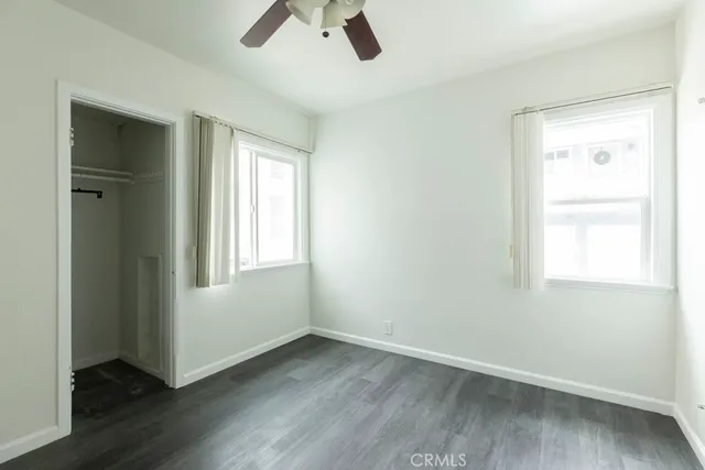 an empty room with wooden floor cabinet and windows