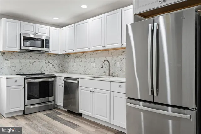 a kitchen with white cabinets and stainless steel appliances