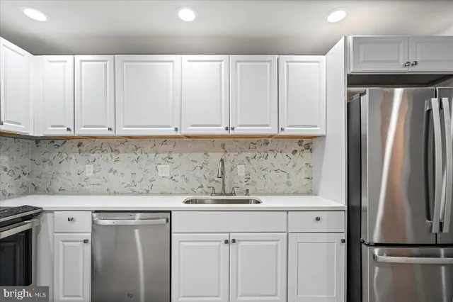 a kitchen with stainless steel appliances granite countertop a refrigerator a stove and white cabinets