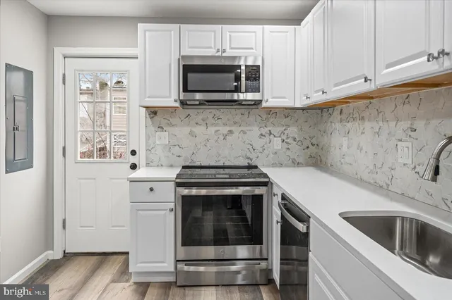 a kitchen with granite countertop white cabinets stainless steel appliances and wooden floor