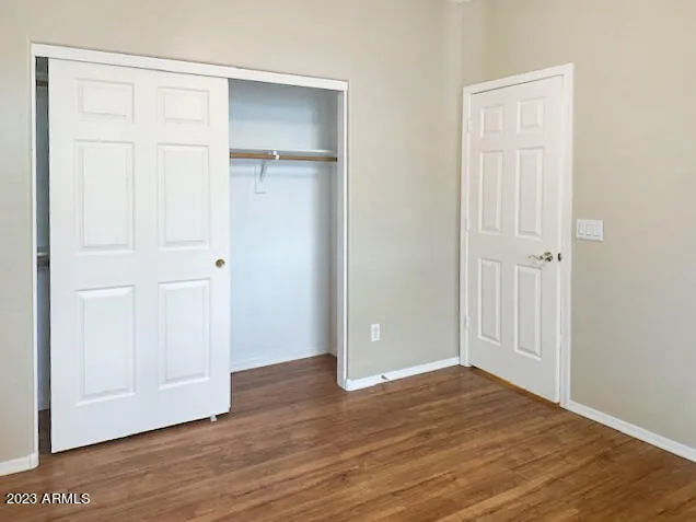 an empty room with wooden floor and closet area