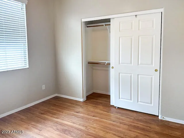 an empty room with wooden floor and closet area