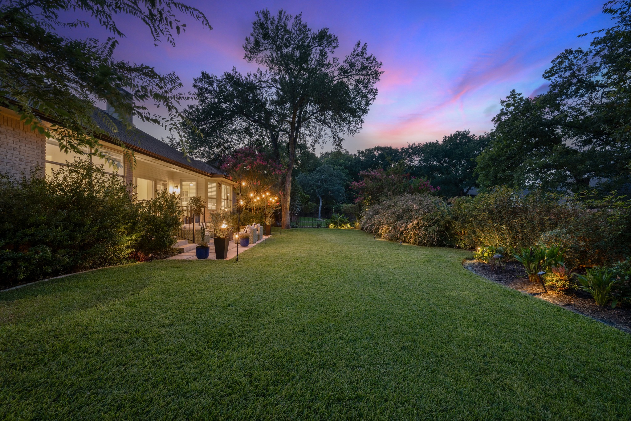 30115 Sawgrass Trail Georgetown, TX 78628 - Photo 20 of 37 A twilight panorama reveals a lush green lawn leading to a charming patio adorned with festive string lights.