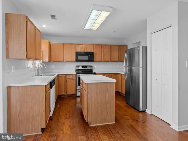 a kitchen with stainless steel appliances granite countertop a stove top oven a refrigerator a sink and dishwasher with wooden floor