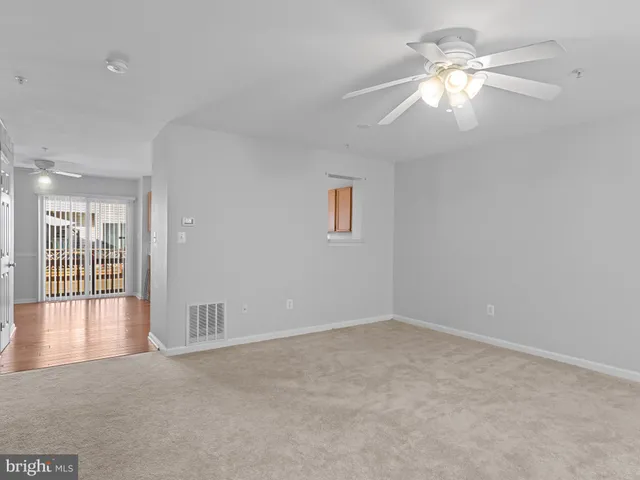 an empty room with chandelier fan and windows
