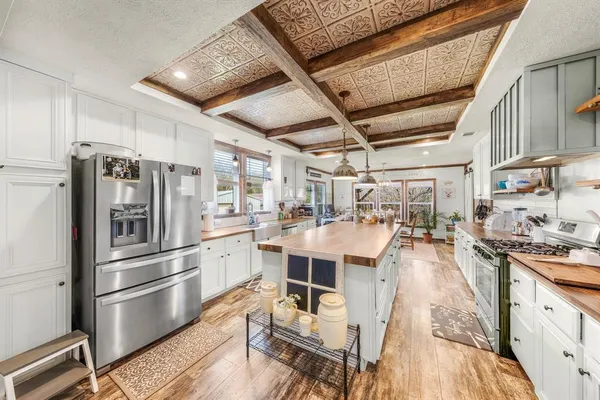a kitchen with stainless steel appliances a stove a sink dishwasher a refrigerator and cabinets with wooden floor
