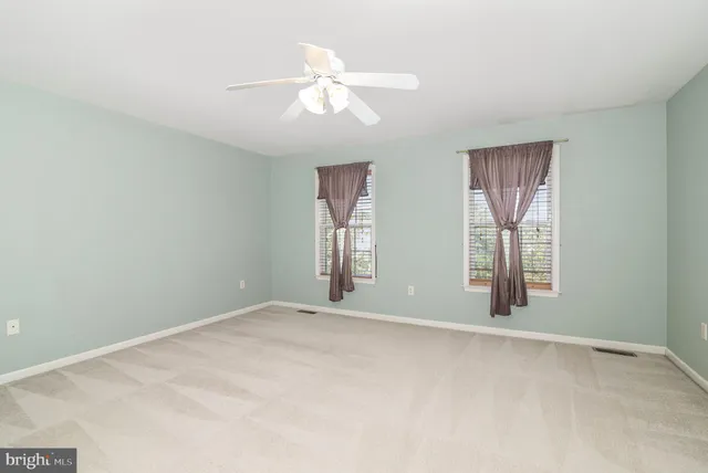 an empty room with windows and chandelier fan