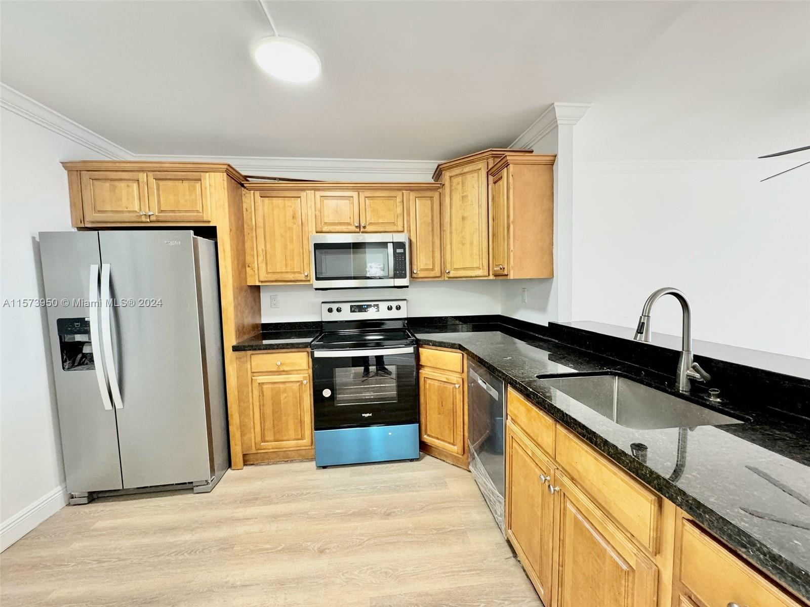 a kitchen with granite countertop a refrigerator stove and sink
