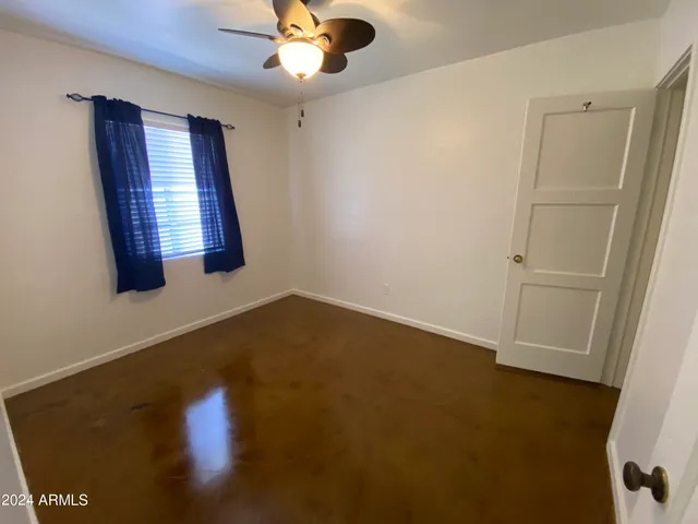 an empty room with a window and ceiling fan
