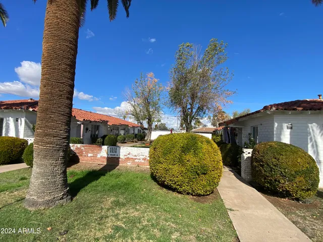 a view of a white house with a yard and potted plants