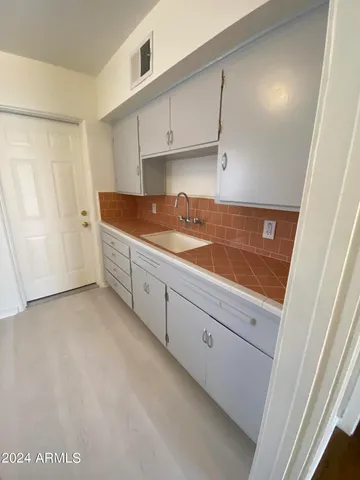 a kitchen with white cabinets and sink