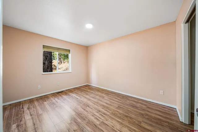 an empty room with wooden floor and window