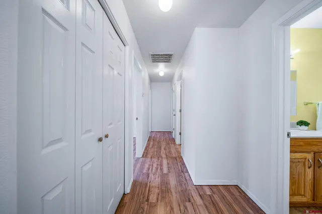 a view of a hallway with wooden floor and a bathroom