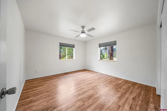 an empty room with windows and a ceiling fan