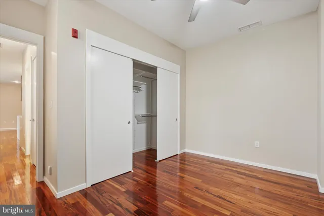 an empty room with wooden floor chandelier fan and windows