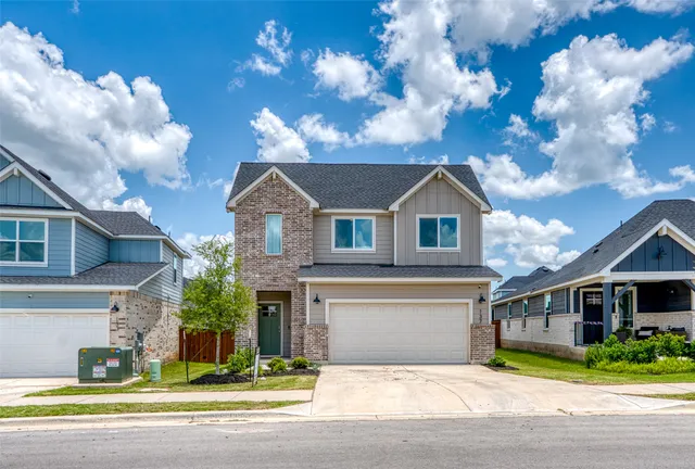 a view of a yard in front of a brick house with large windows