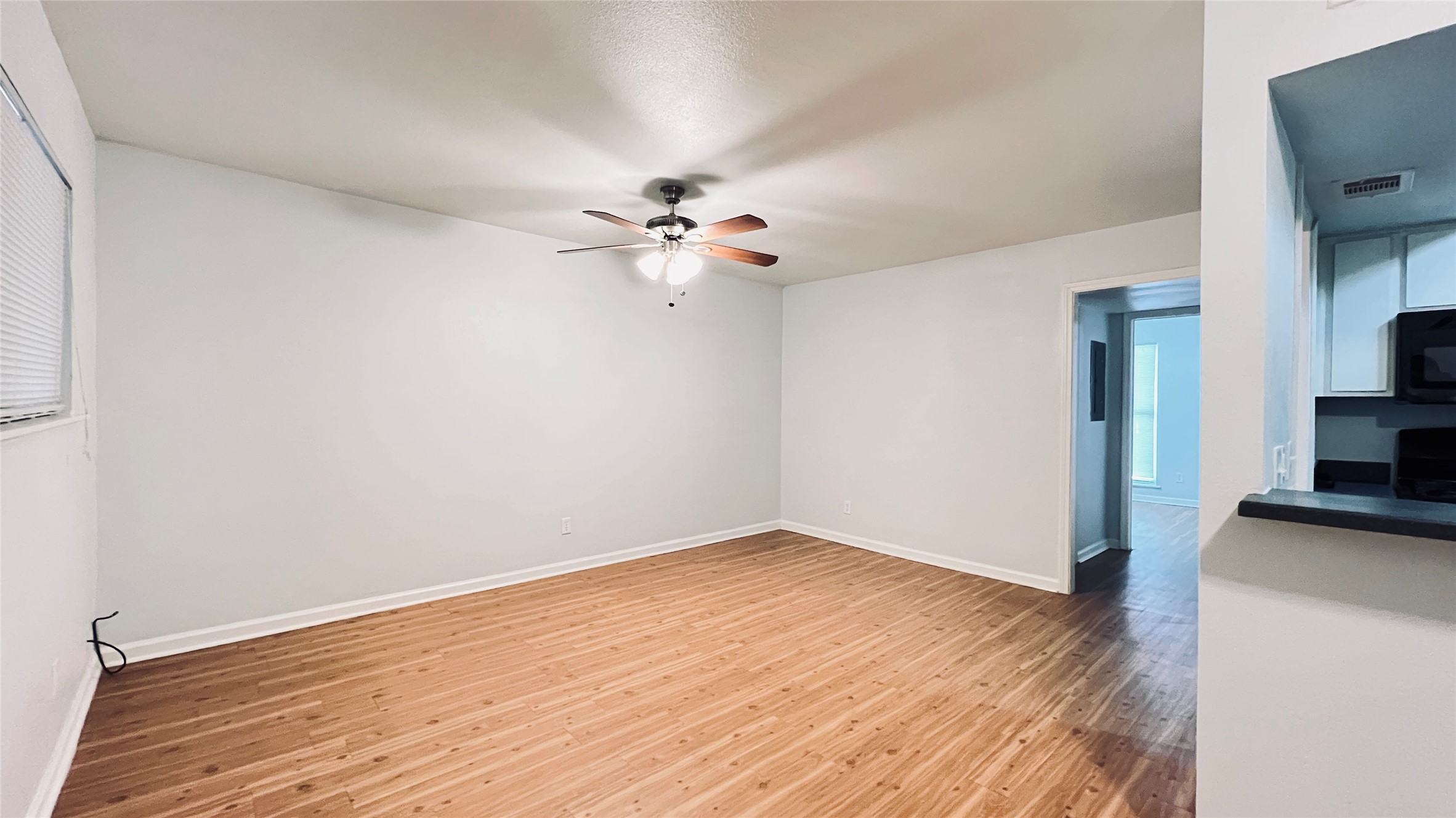 2301 Ohlen Road, Unit 209 Austin, TX 78757 - Photo 8 of 10 A versatile living area features warm wood-look flooring and a functional ceiling fan, connecting to the kitchen.