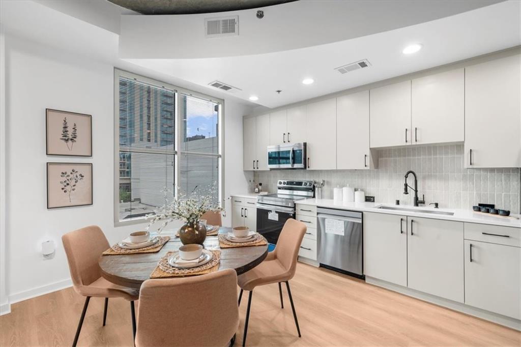 250 Pharr Road Northeast, Unit 704 Atlanta, GA 30305 - Photo 5 of 53 a kitchen with a dining table chairs and white cabinets