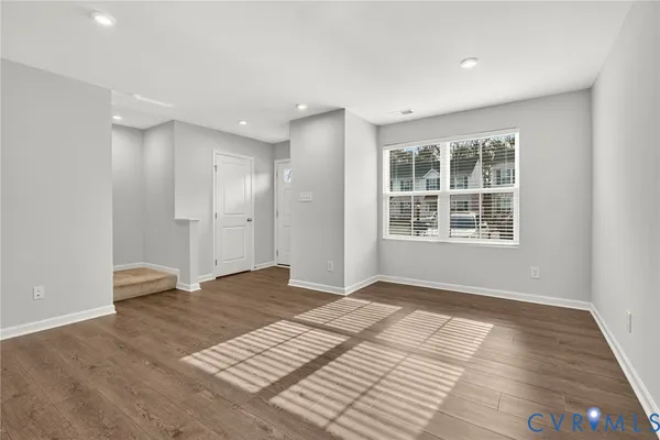 a view of an empty room with wooden floor and windows