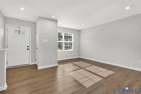 an empty room with wooden floor cabinet and windows