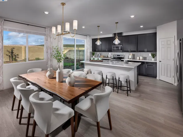 a open dining room with stainless steel appliances granite countertop a dining table chairs refrigerator and kitchen view