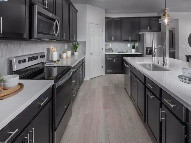 a kitchen with stainless steel appliances wooden cabinets granite counter tops a stove a sink and a refrigerator