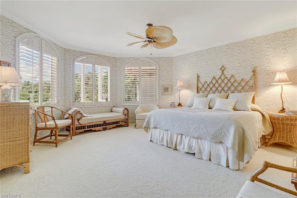 4588 Silver Fox Drive Naples, FL 34119 - Photo 20 of 35 a spacious bedroom with a bed and a chandelier