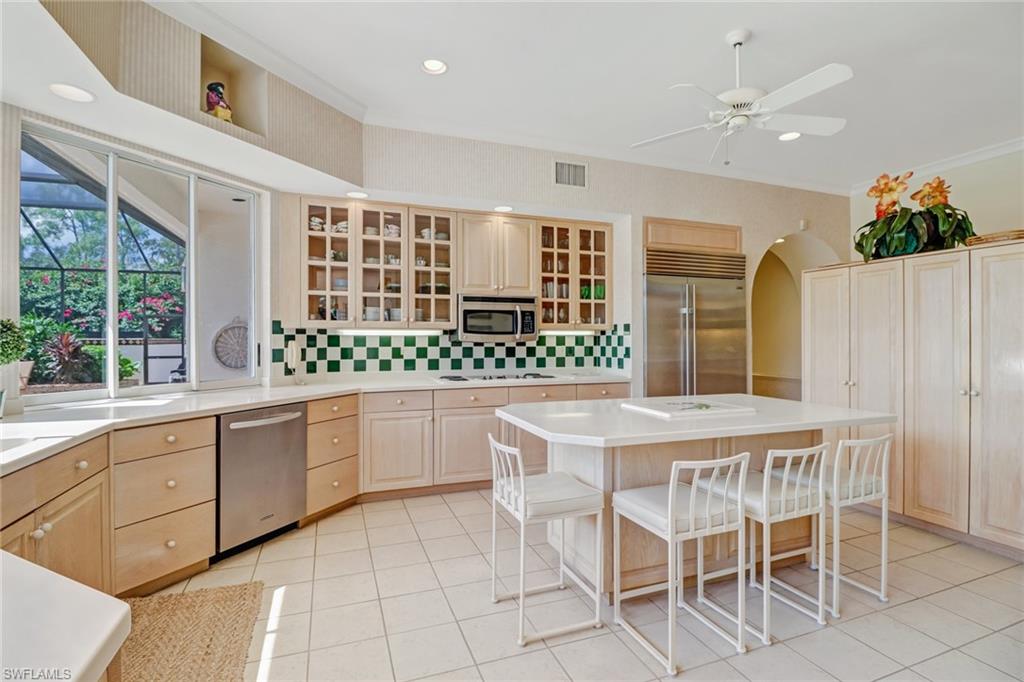 4588 Silver Fox Drive Naples, FL 34119 - Photo 10 of 35 a kitchen with a stove a sink and white cabinets with wooden floors