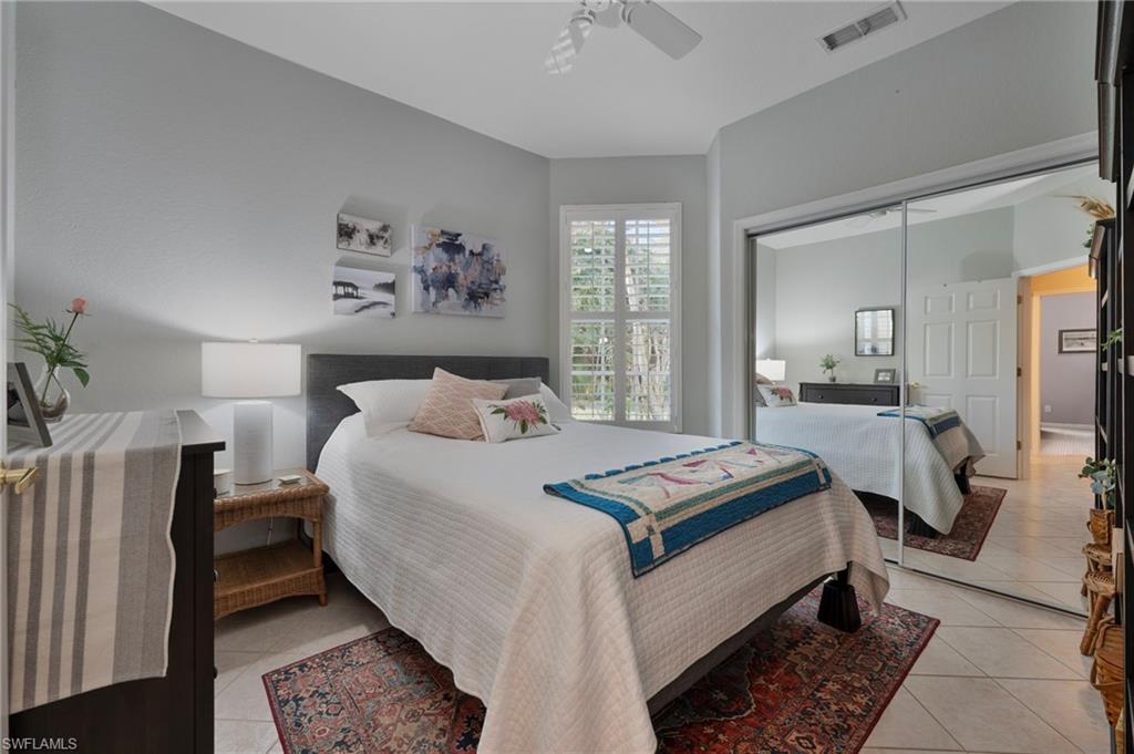 4695 Winged Foot Court, Unit 101 Naples, FL 34112 - Photo 12 of 23 a bedroom with bed and a large mirror