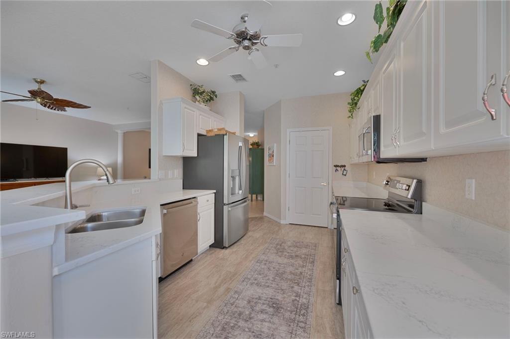 4695 Winged Foot Court, Unit 101 Naples, FL 34112 - Photo 5 of 23 a kitchen with refrigerator cabinets and a sink