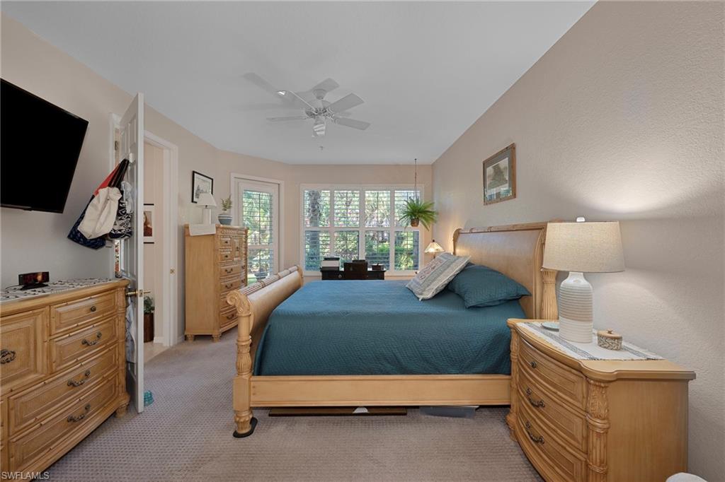 4695 Winged Foot Court, Unit 101 Naples, FL 34112 - Photo 9 of 23 a bedroom with a bed and a flat tv screen on the dresser