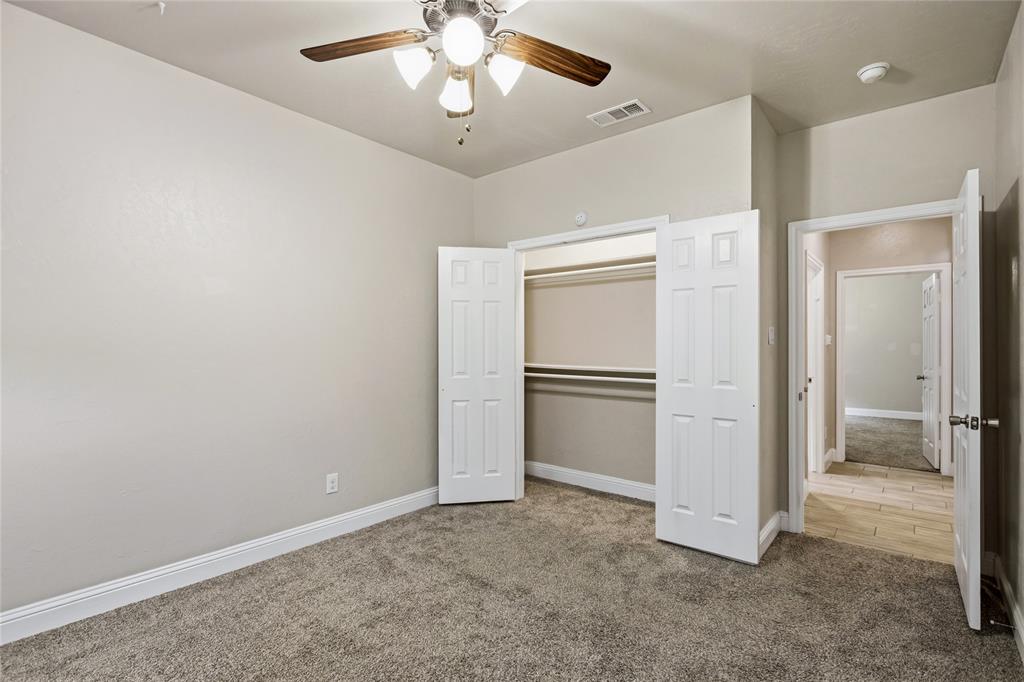 1502 Reed Street Greenville, TX 75401 - Photo 21 of 26 Carpeted room with a ceiling fan light fixture, bifold closet doors, and wood-finish flooring extending into the hallway