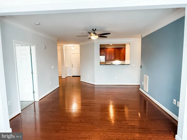 a view of empty room with wooden floor and fan