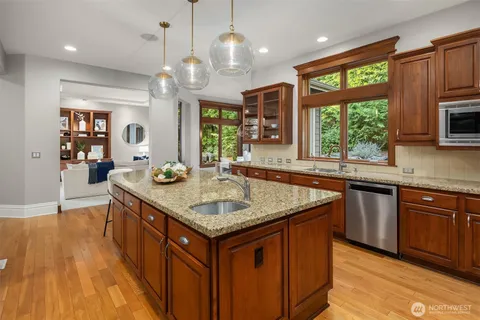 a kitchen with stainless steel appliances granite countertop wooden cabinets a center island and a window