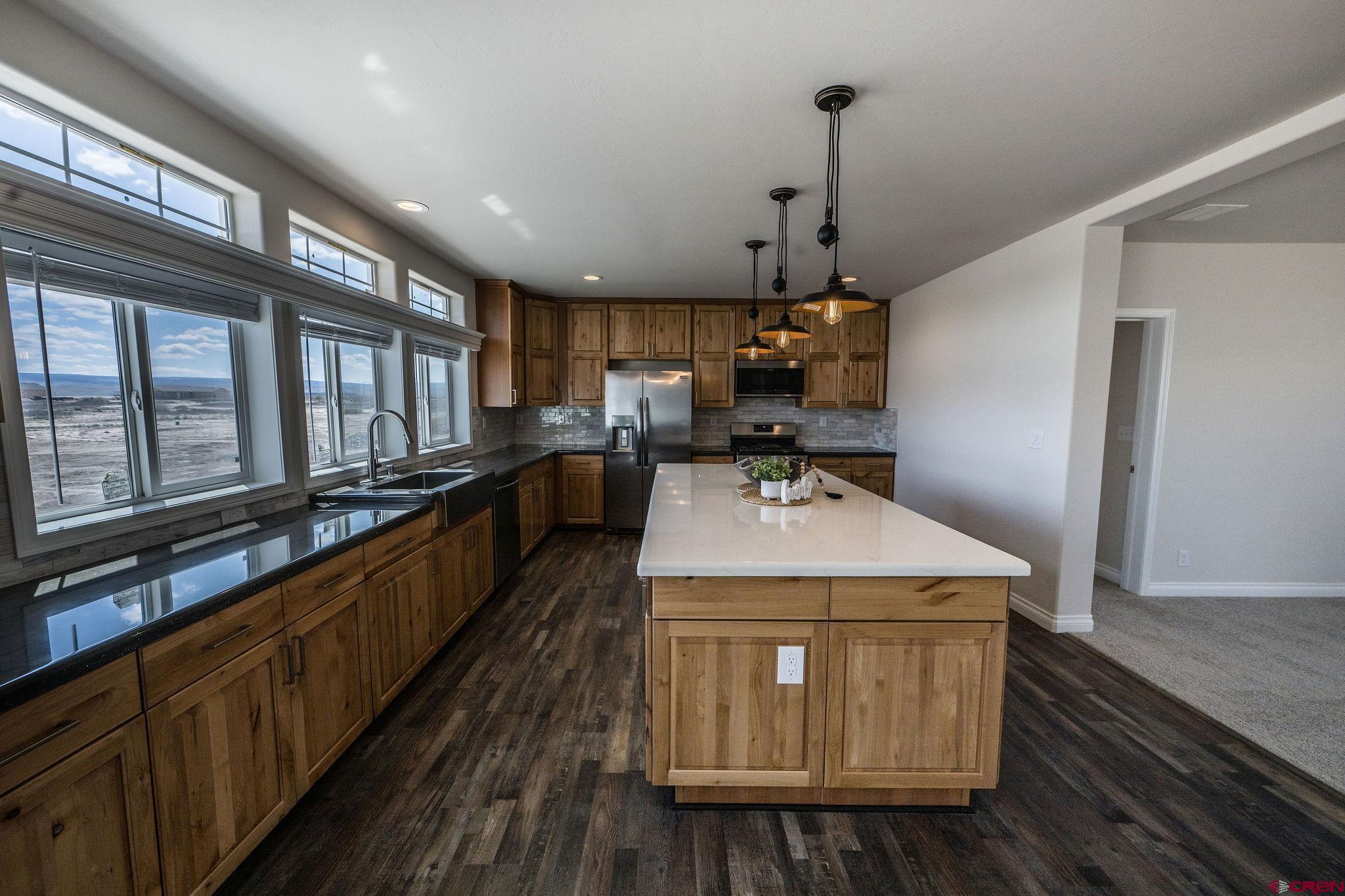 1246 H25 Road Delta, CO 81416 - Photo 3 of 31 a kitchen with kitchen island granite countertop wooden cabinets and white appliances