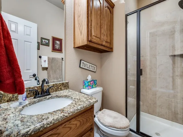 a bathroom with a granite countertop sink a toilet and shower