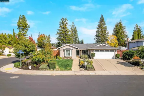a front view of a house with a garden and trees