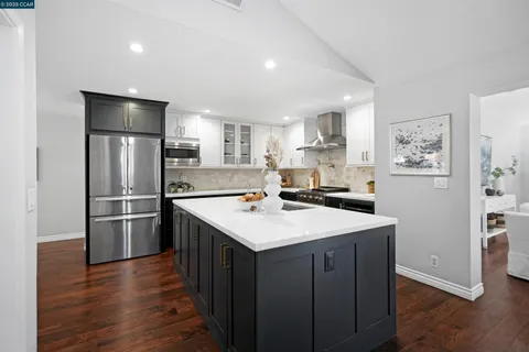 a kitchen with kitchen island a refrigerator sink and wooden floor