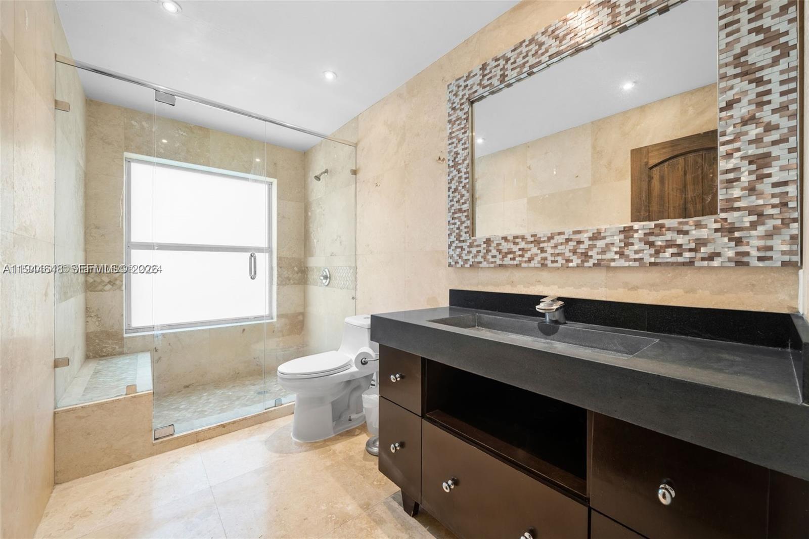 6411 Southwest 185th Way Southwest Ranches, FL 33332 - Photo 28 of 32 a bathroom with a granite countertop sink a toilet a mirror and a bathtub