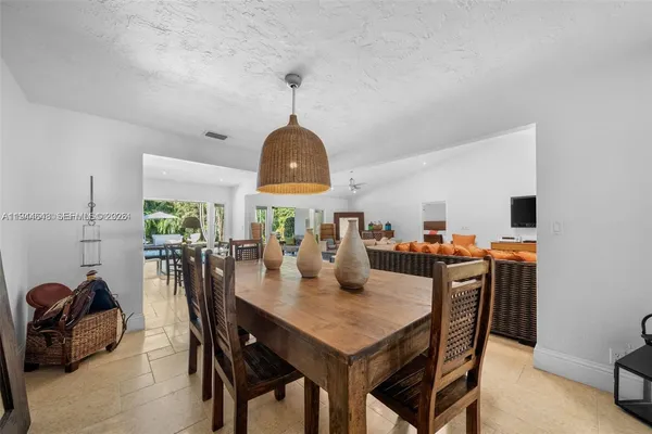 a view of a dining room and livingroom with furniture wooden floor a rug a painting and a chandelier