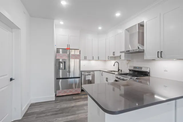 a kitchen with stainless steel appliances granite countertop a sink a stove and a refrigerator