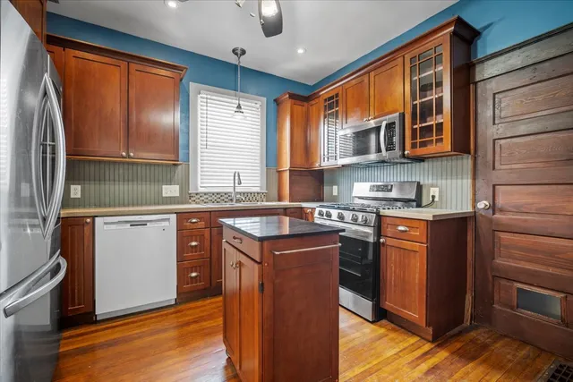 a kitchen with stainless steel appliances granite countertop a sink stove cabinets and wooden floor