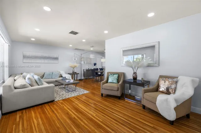 a living room with furniture a wooden floor and kitchen view