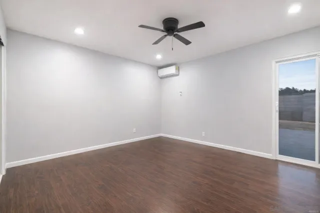 an empty room with wooden floor and ceiling fan