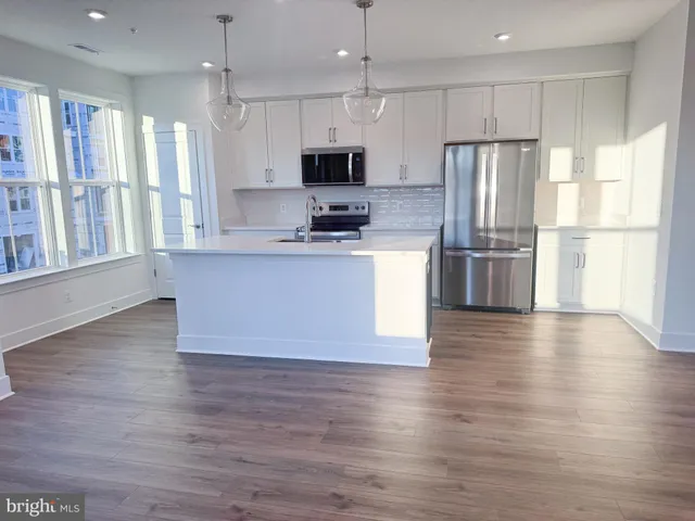 a large kitchen with stainless steel appliances granite countertop a refrigerator a stove top oven a sink dishwasher and wooden floor