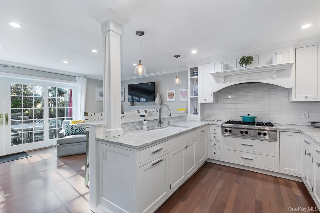 94 Round Hill Road Scarsdale, NY 10583 - Photo 13 of 46 View of the renovated, all-white kitchen with Italian marble countertops, upscale stainless appliances, and peninsula with counter seating and storage.