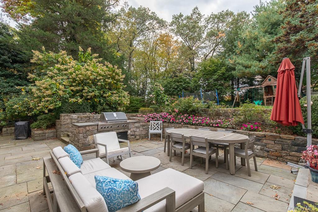 94 Round Hill Road Scarsdale, NY 10583 - Photo 17 of 46 Stone patio featuring a custom built-in cooking area with grill is accessible from the formal living room and the family room.